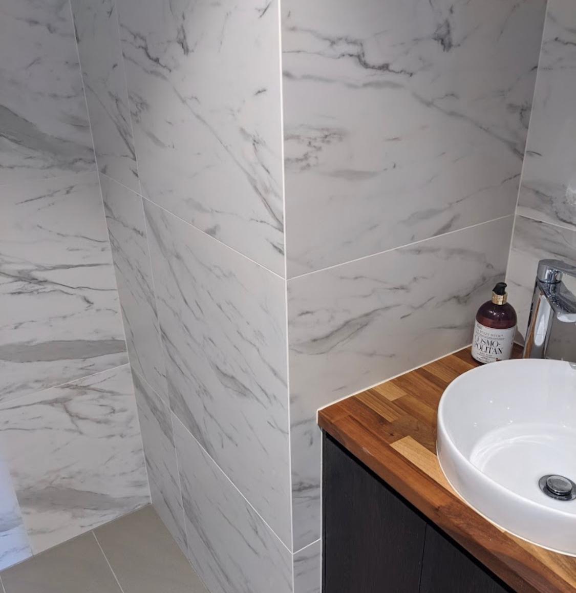 Marble-look bathroom wall with mitred corner and timber vanity — Perth Tiling WA project
